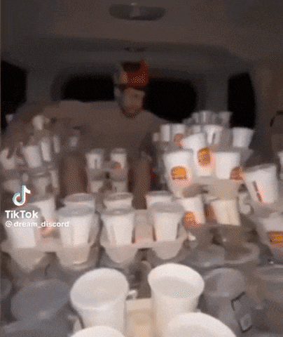 a man is standing in the back of a van filled with plastic cups and containers .