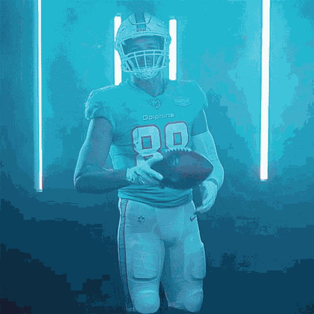 a dolphins football player holds a football in his hand