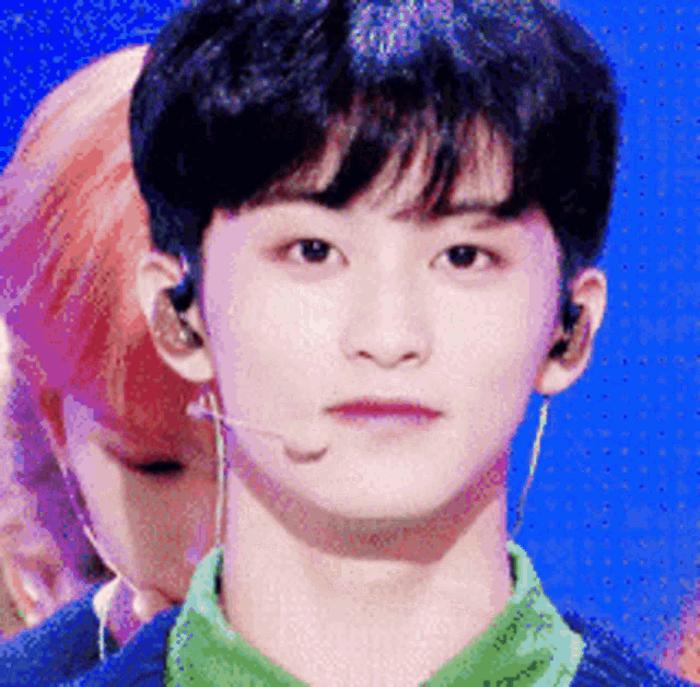 a young man wearing a green shirt and ear buds