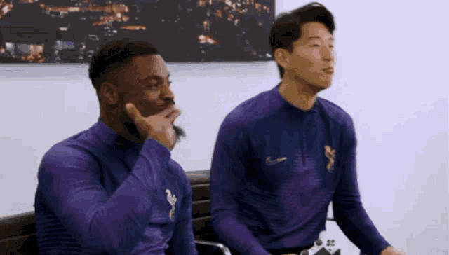 two soccer players are sitting on a bench in front of a spurs tv logo