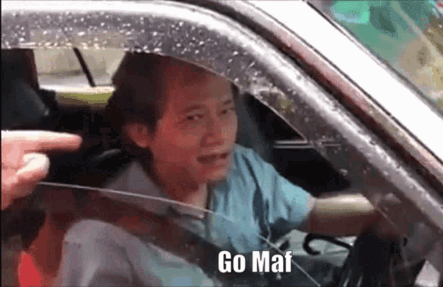 a man is sitting in a car with the words go maf written on the window