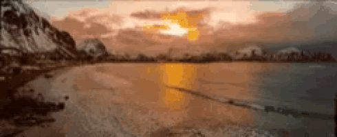 a blurry picture of a beach at sunset with mountains in the background .