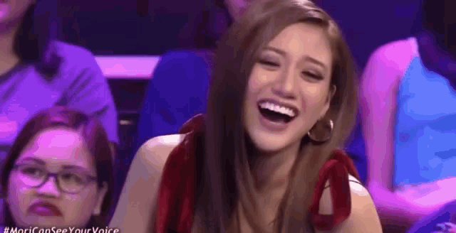 a woman is laughing while sitting in a theatre .