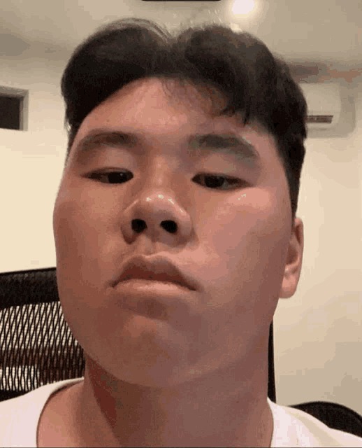 a close up of a man 's face with a black chair behind him
