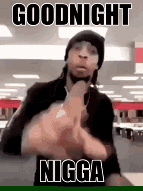 a man in a black hat is giving the middle finger in a room with the words `` goodnight nigga '' .