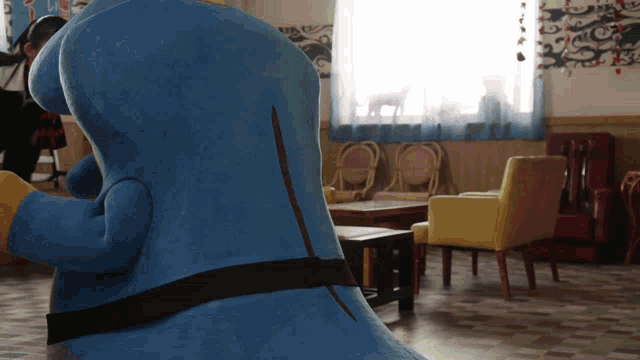 a blue stuffed animal sitting in a room with chairs and tables