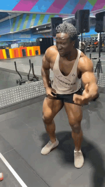 a man in a gym wearing a white tank top with the word hyperwear on it