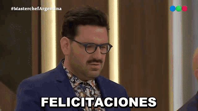 a man in a suit and glasses says felicitaciones on a television screen