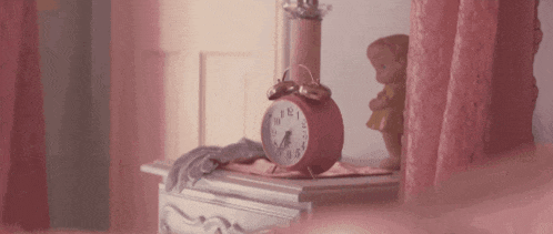 a pink alarm clock is sitting on a pink nightstand