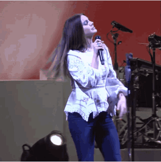 a woman singing into a microphone while dancing on a stage