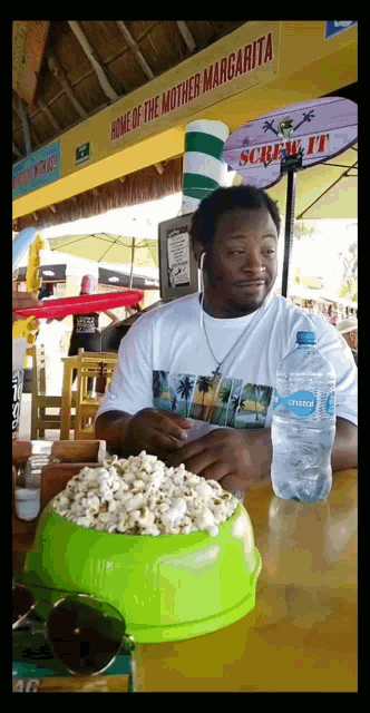 a man sitting at a table with a bowl of popcorn and a bottle of sierra water