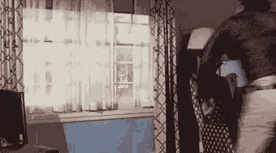a man is standing in a living room next to a window holding a bag .
