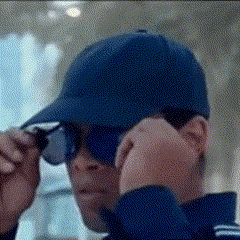 a man wearing a blue hat and sunglasses adjusts his sunglasses