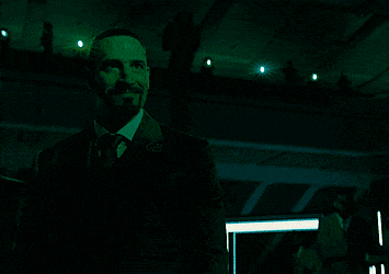 a man in a suit and tie stands in a dark room with the words kill them all above him