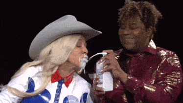 a woman in a cowboy hat is pouring milk on a man