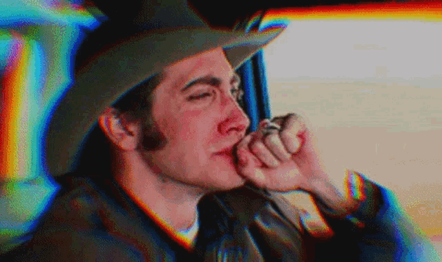 a man in a cowboy hat is smoking a cigarette in a car