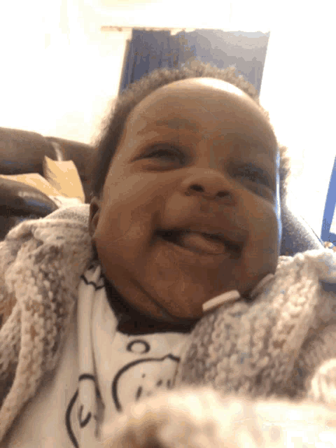a baby is smiling and wearing a sweater that says ' snoopy ' on it