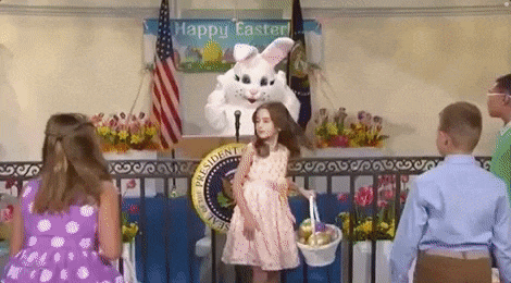 a little girl is holding a basket of easter eggs in front of a bunny rabbit costume .