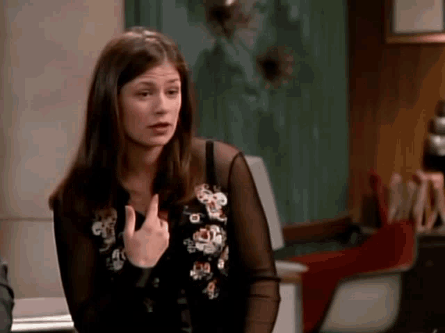 a woman wearing a black shirt with flowers on it is giving a middle finger