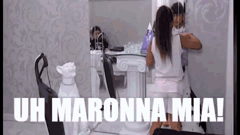 a woman is standing in front of a mirror with the words uh maronna mia written above her