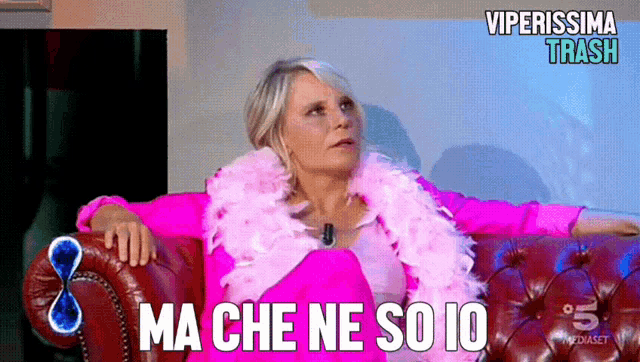 a woman in a pink outfit sits on a couch with the words ma che ne so io