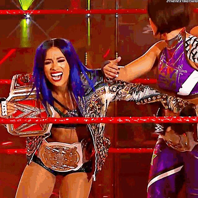 a woman with blue hair is holding a wrestling belt in a ring .