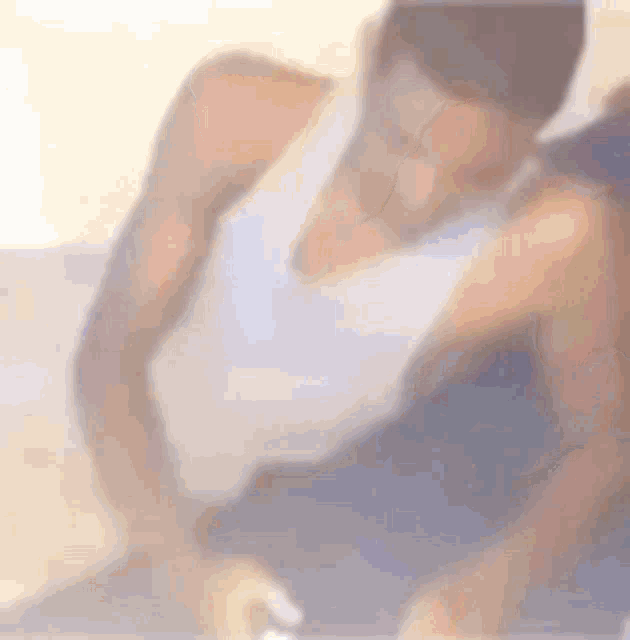 a man in a white tank top is sitting on a bed .