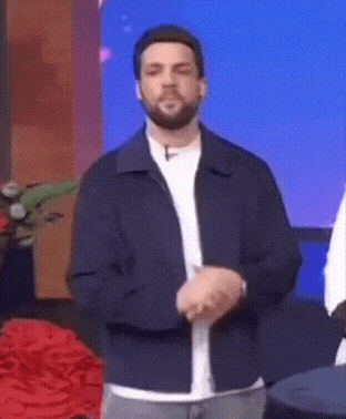 a man with a beard is standing in front of a blue background .