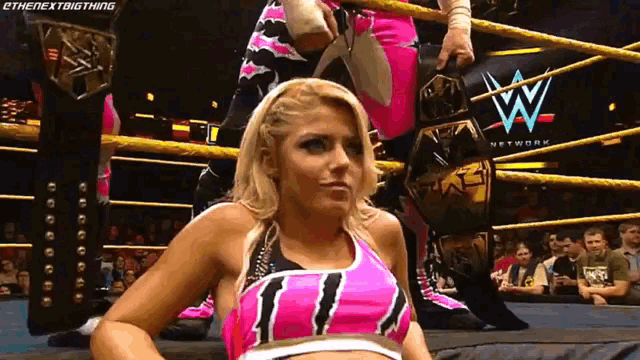 a woman in a wrestling ring with a wwe logo on the wall behind her