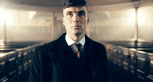 a man in a suit and tie is standing in a church with rows of pews .