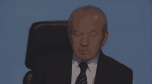 an older man in a suit and tie is sitting in a chair