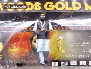 a man is standing on a stage wearing a medal and dancing .
