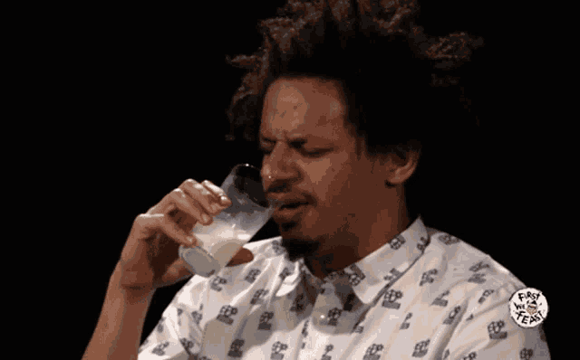 a man drinking a glass of milk with a shirt that says ' fast n ' easy ' on it