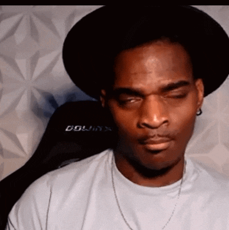 a man wearing a hat and a white t-shirt is making a funny face .