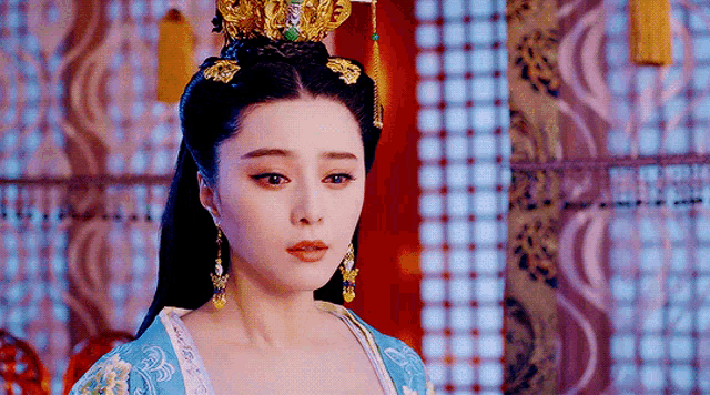 a woman wearing a crown and earrings is looking at the camera