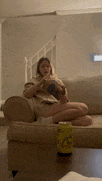 a woman sits on a couch reading a book next to a can of lemonade