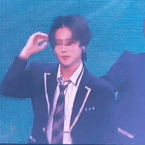 a man in a suit and tie is making a funny face while another man looks on .