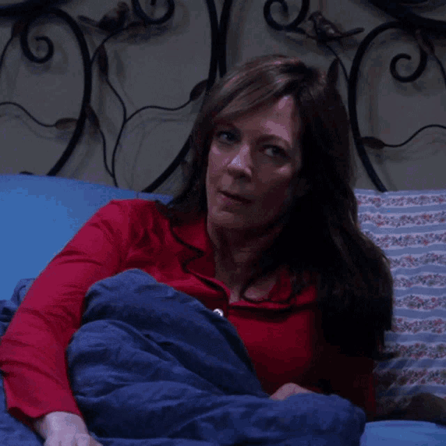 a woman in a red shirt is laying in bed