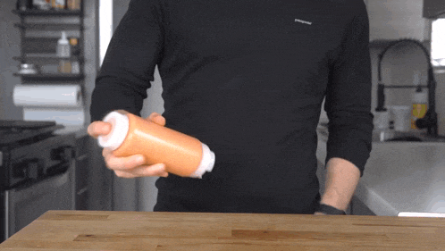 a man wearing a black patagonia shirt is holding a bottle