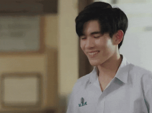a young man in a white shirt is smiling in a hallway .