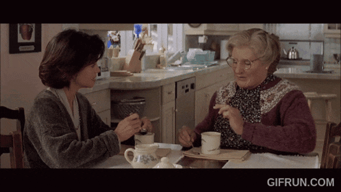two women sit at a table with a gifrun.com watermark on the bottom right