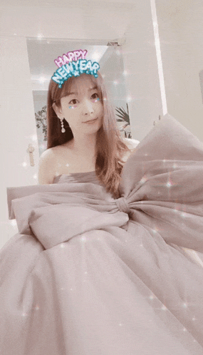 a woman in a gray dress with a bow and a happy new year sticker on her head