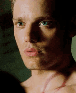 a close up of a man 's face with blue eyes and red lips