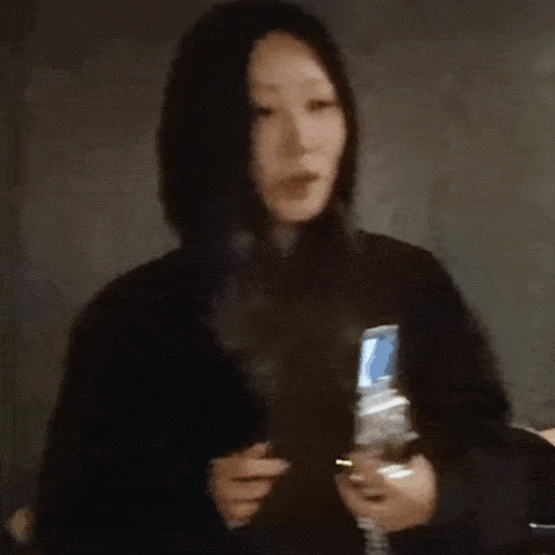 a woman is holding a bottle of water and a cell phone