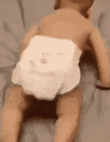 a baby in a diaper is crawling on the floor .