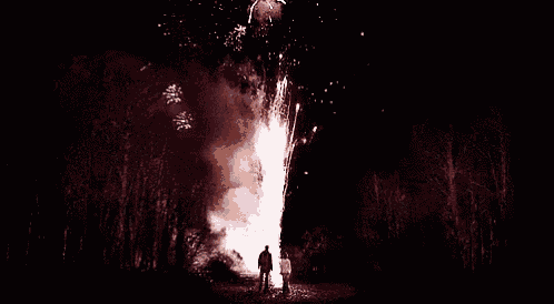 two people standing in front of a large fireworks display