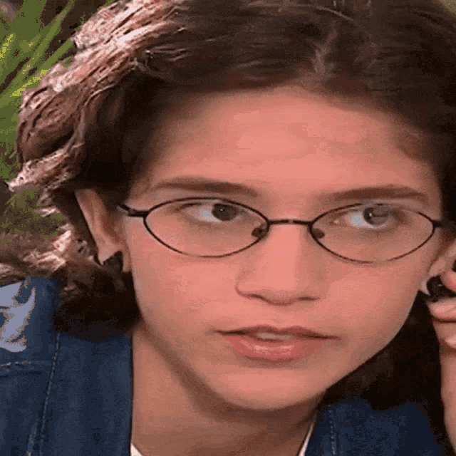 a close up of a girl wearing glasses and a blue shirt