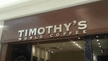 a sign for timothy 's world coffee is above the store