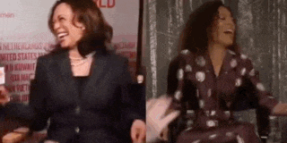 a woman in a suit and polka dot dress is laughing while standing next to another woman in a chair .