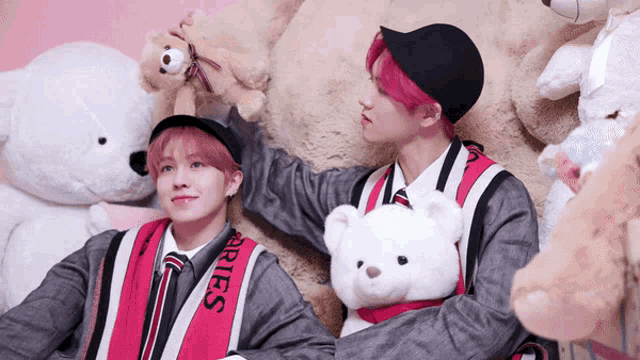 a boy with pink hair is holding a teddy bear that says aries